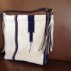 Off-white & dark blue bag with dark & light grey shoulder strap & fringe. 14 x 14"