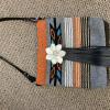 A white hair-on cow hide flower accents this beautiful grey, burnt orange, & turquoise bag.